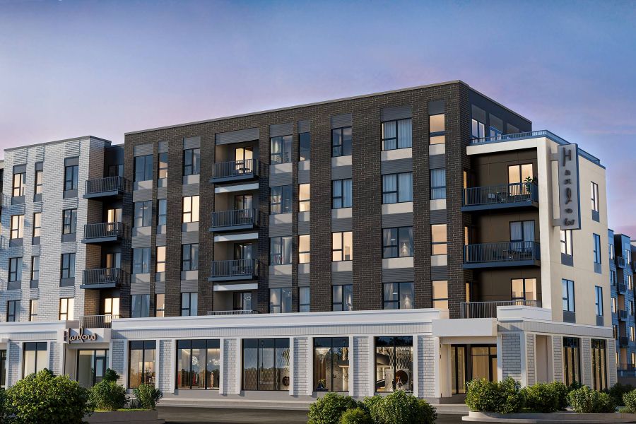 Modern five-story apartment building with balconies, large windows, and ground-floor retail at sunset at Harlow.